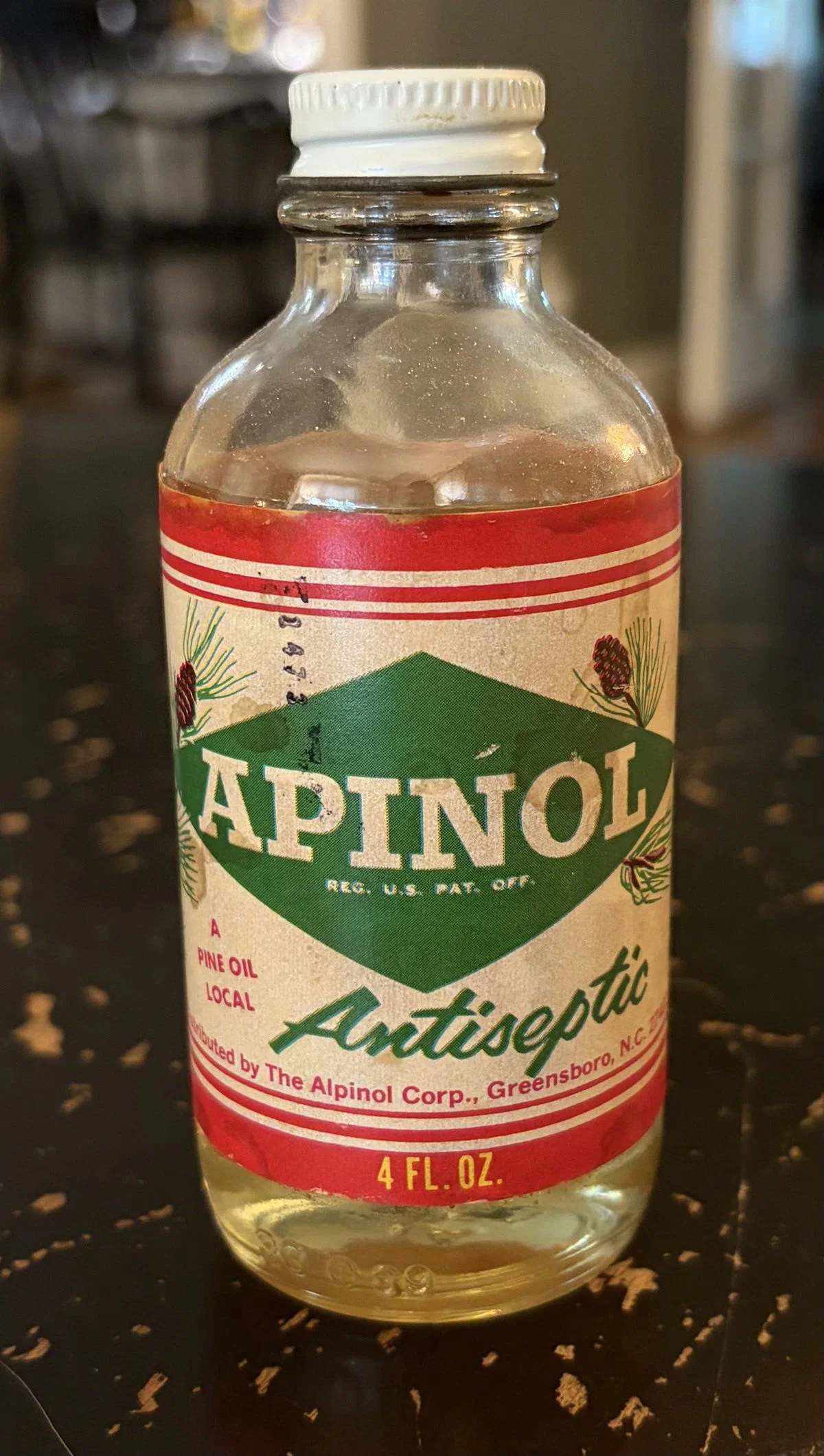 A vintage glass bottle of Apinol pine oil antiseptic on a table.